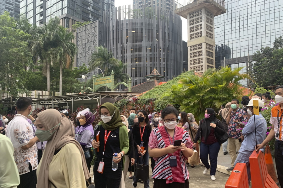 People wait outside as they have to evacuate their office buildings following an earthquake, at the main business district in Jakarta, Indonesia, Friday, Jan. 14, 2022. A powerful earthquake shook parts of Indonesia's main island of Java on Friday, causing buildings in the capital to sway, but there were no immediate reports of serious damage or casualties. Officials said there was no danger of a tsunami.