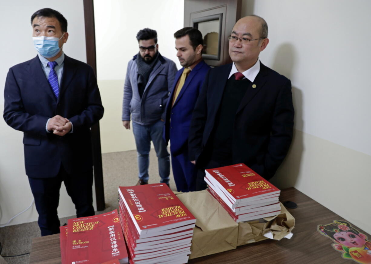 Chinese lecturer, Zhiwei Hu, left, teachers and officials of the Chinese Language Department stand in front of Chinese language books intended for students in Salahaddin University in Irbil, Iraq, Wednesday, Jan. 19, 2021. The Chinese language school in northern Iraq is attracting students who hope to land jobs with a growing number of Chinese companies in the oil, infrastructure, construction, and telecommunications sectors in the region.