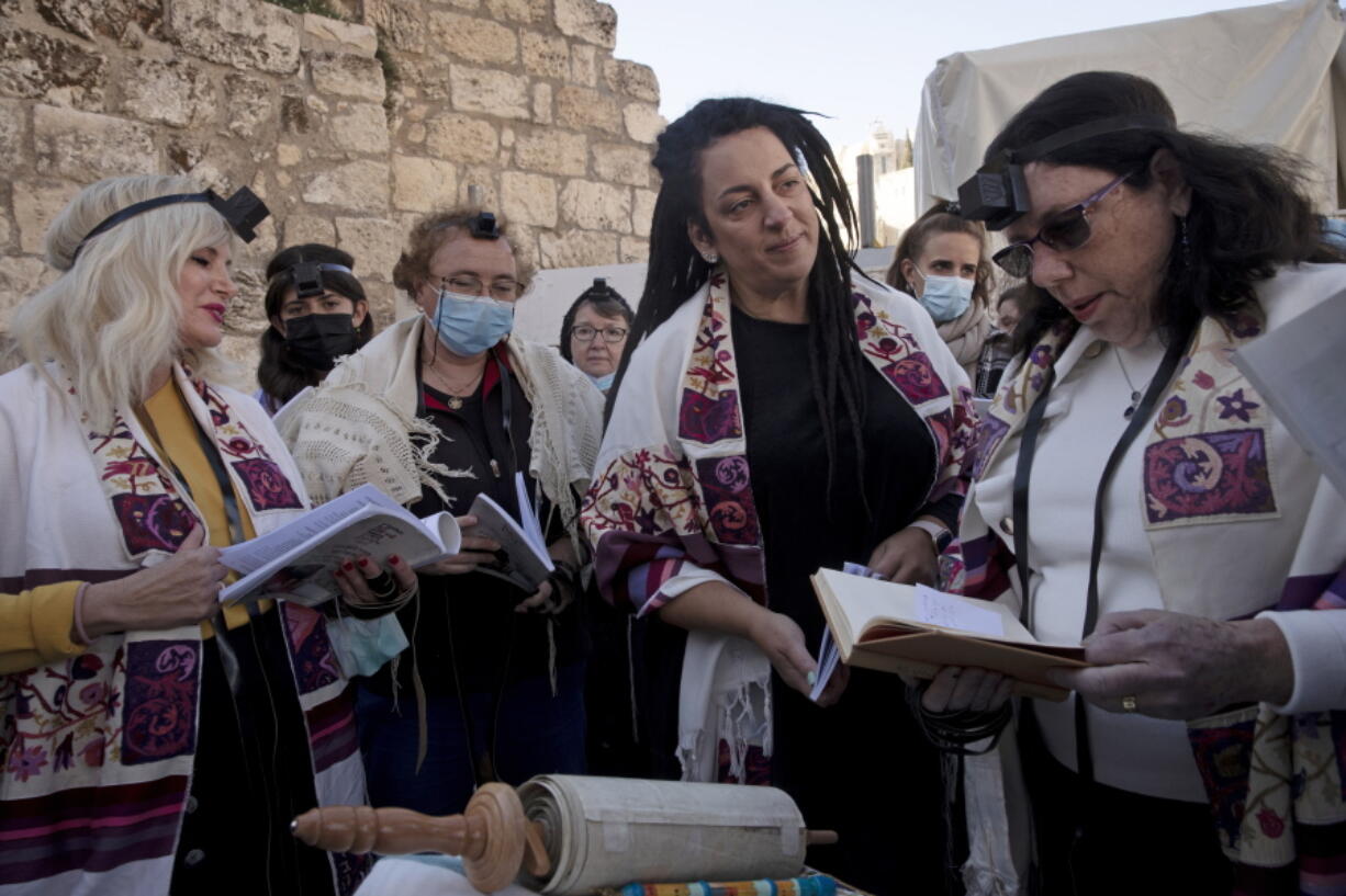 FILE - Members of Women of the Wall gather around a Torah scroll the group smuggled in for their Rosh Hodesh prayers marking the new month, at the Western Wall where women are forbidden from reading from the Torah, Sunday, Dec. 5, 2021. When Israel's new government took office last June, it indicated it would press ahead on an egalitarian prayer site at Jerusalem's Western Wall -- a sensitive holy site that has emerged as a point of friction between Jews over how prayer is conducted there.