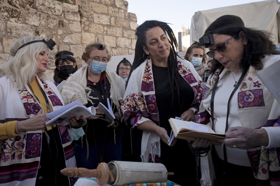 FILE - Members of Women of the Wall gather around a Torah scroll the group smuggled in for their Rosh Hodesh prayers marking the new month, at the Western Wall where women are forbidden from reading from the Torah, Sunday, Dec. 5, 2021. When Israel's new government took office last June, it indicated it would press ahead on an egalitarian prayer site at Jerusalem's Western Wall -- a sensitive holy site that has emerged as a point of friction between Jews over how prayer is conducted there.