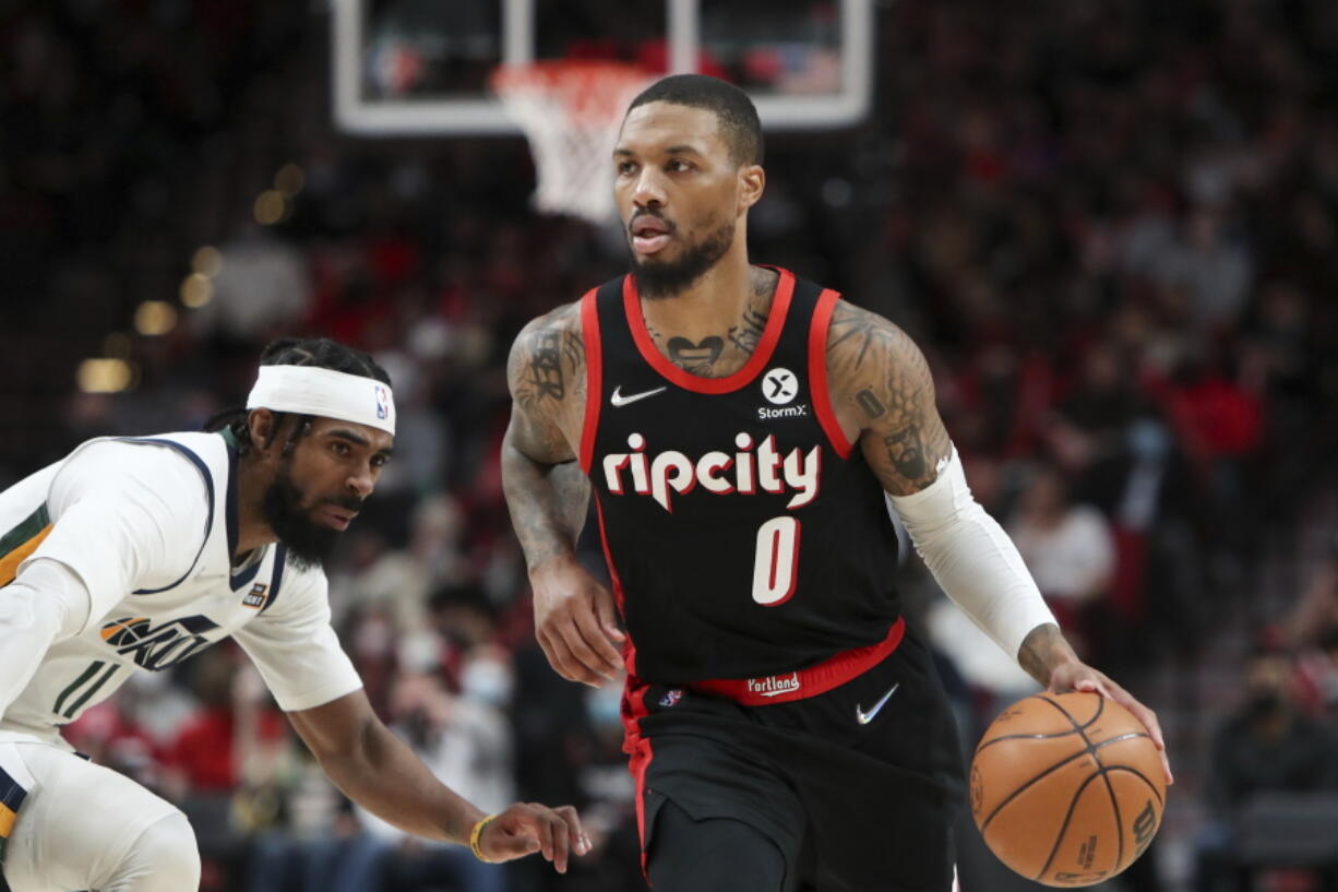 Portland Trail Blazers guard Damian Lillard dribbles past Utah Jazz guard Mike Conley during the second half of an NBA basketball game in Portland, Ore., Wednesday, Dec. 29, 2021. The Jazz won 120-105.
