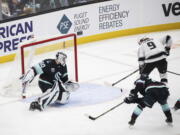 Los Angeles Kings center Adrian Kempe (9) chips the puck in past Seattle Kraken goaltender Chris Driedger (60) to score during the first period of an NHL hockey game, Saturday, Jan. 15, 2022, in Seattle.