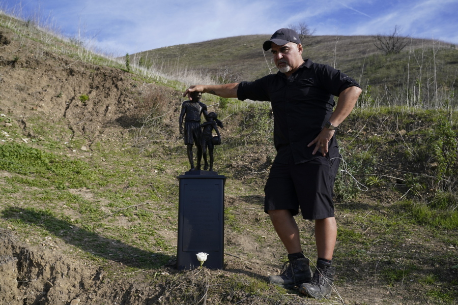 Dan Medina stands next to a statue he created in memory of former Los Angeles Lakers NBA basketball player Kobe Bryant and his daughter, Gianna, on Wednesday, Jan. 26, 2022, in Calabasas, Calif. The statue was carried by the artist on a trail near where Bryant, his daughter, and seven other people died in a helicopter crash two years ago Wednesday.