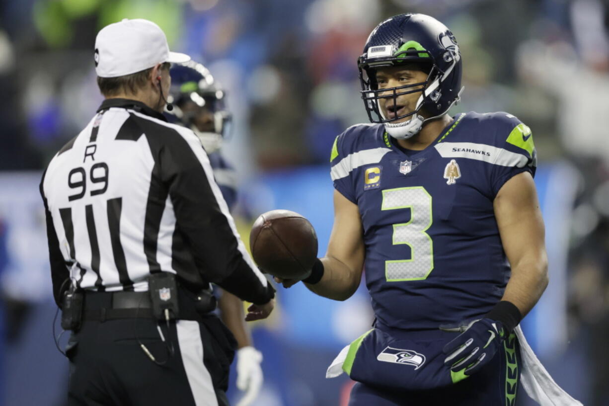Seattle Seahawks quarterback Russell Wilson (3) hands the game ball to referee Tony Corrente (99) after an NFL football game against the Detroit Lions, Sunday, Jan. 2, 2022, in Seattle.