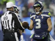 Seattle Seahawks quarterback Russell Wilson (3) hands the game ball to referee Tony Corrente (99) after an NFL football game against the Detroit Lions, Sunday, Jan. 2, 2022, in Seattle.