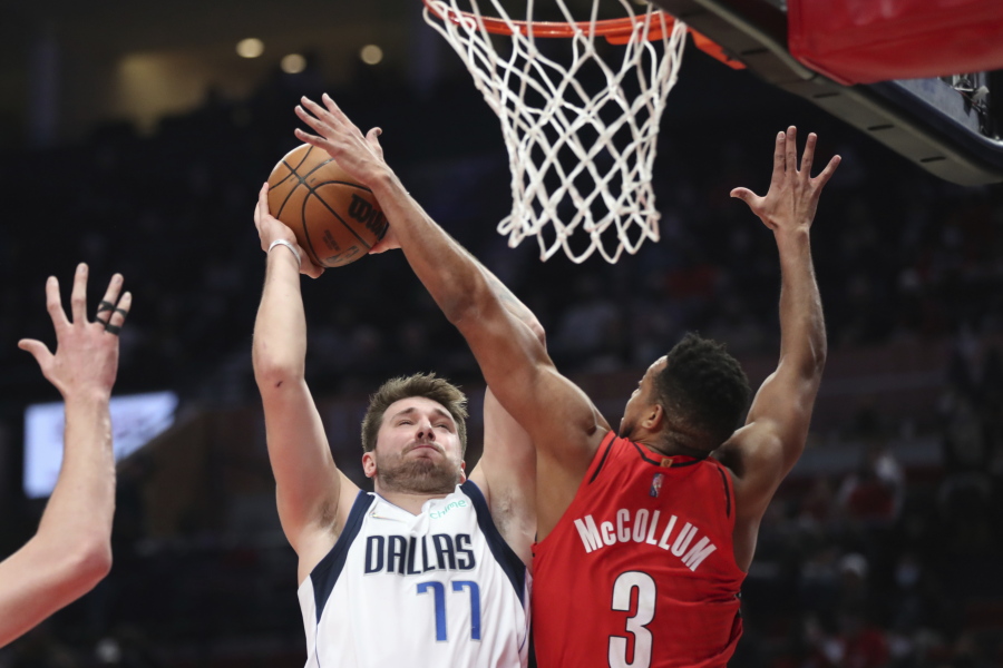 Dallas Mavericks guard Luka Doncic is fouled by Portland Trail Blazers guard CJ McCollum during the first half of an NBA basketball game in Portland, Ore., Wednesday, Jan. 26, 2022.