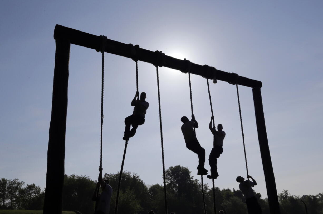 FILE - Freshman midshipmen, known as plebes, climb ropes on an obstacle course during Sea Trials, a day of physical and mental challenges that caps off the freshman year at the U.S. Naval Academy in Annapolis, Md., May 13, 2014. The Navy is adding two weeks to boot camp in a major overhaul aimed at improving recruits' war fighting and emergency skills while also focusing on character issues such as sexual assault, hazing and extremism in the ranks. Navy officials say expanding boot camp to 10 weeks will provide more leadership training and ensure sailors are reporting to their jobs better prepared for duty.
