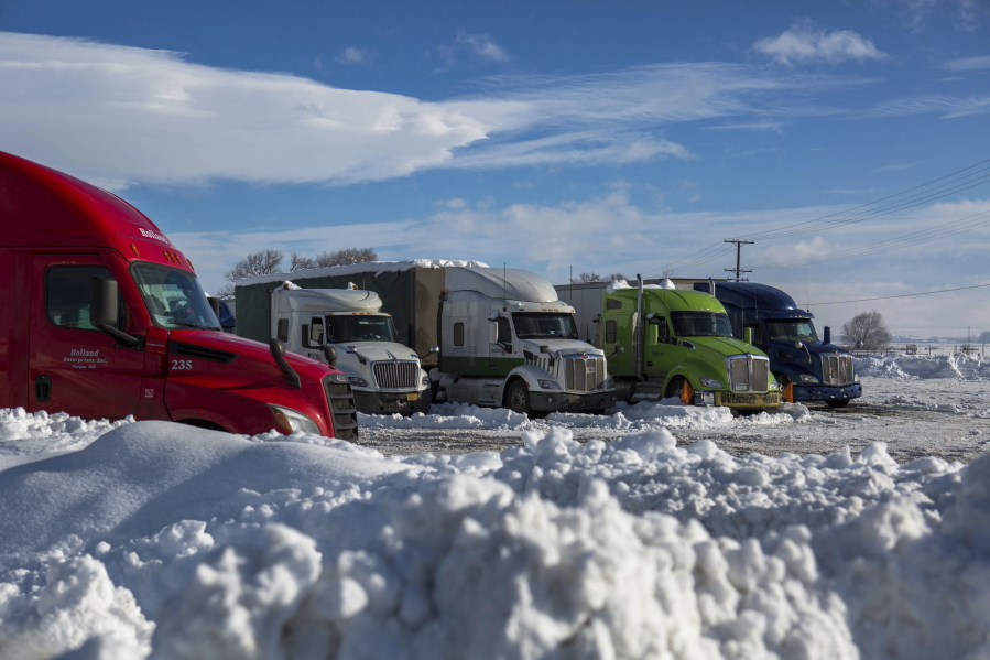 Semitrucks are seen parked near Interstate 90 in Ellensburg, Wash., on Friday, Jan. 7, 2022. The Snoqualmie Pass remained closed as of Friday due hazardous driving conditions.
