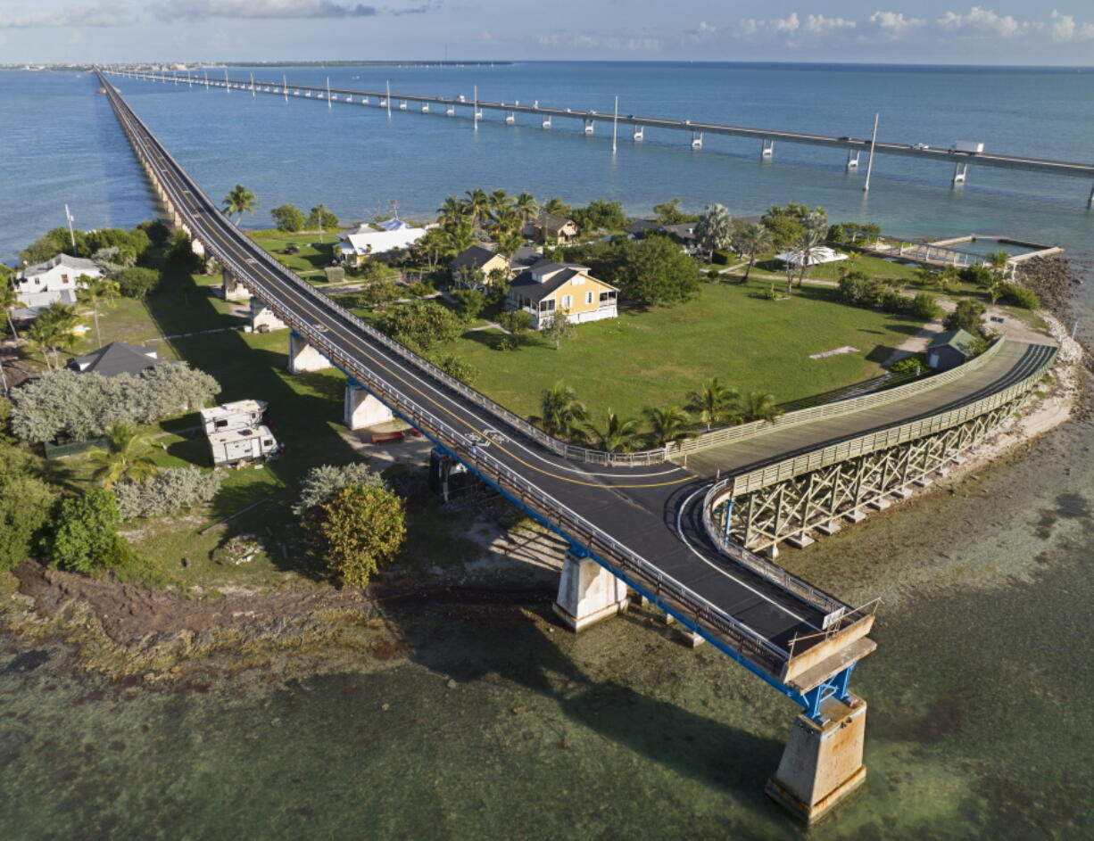 This Monday, Jan. 10, 2022, drone aerial photo provided by the Florida Keys News Bureau shows the Old Seven Mile Bridge ready for its Wednesday, Jan. 12, 2022, reopening to pedestrians, bicyclists, anglers and visitors to Pigeon Key (island shown in photo). The old bridge originally was part of Henry Flagler's Florida Keys Over-Sea Railroad that was completed in 1912. The railroad ceased operations in 1935 and was converted into a highway that opened in 1938. In 1982, construction was completed on a new Seven Mile Bridge, behind, that continues to carry motor vehicles between the South Florida mainland throughout the Keys to Key West.