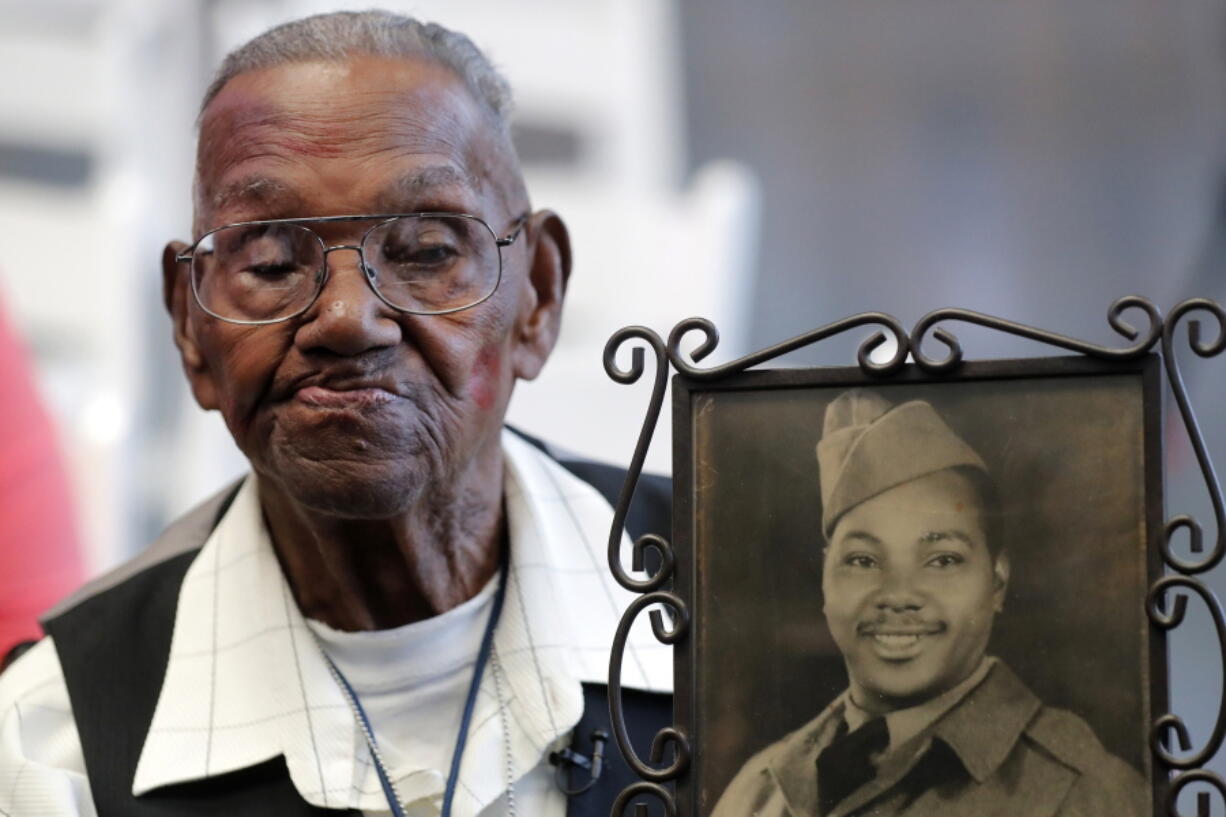 World War II veteran Lawrence Brooks holds a photo of himself taken in 1943, as he celebrates his 110th birthday Sept. 12, 2019, at the National World War II Museum in New Orleans. Brooks died Jan. 5 at age 112.
