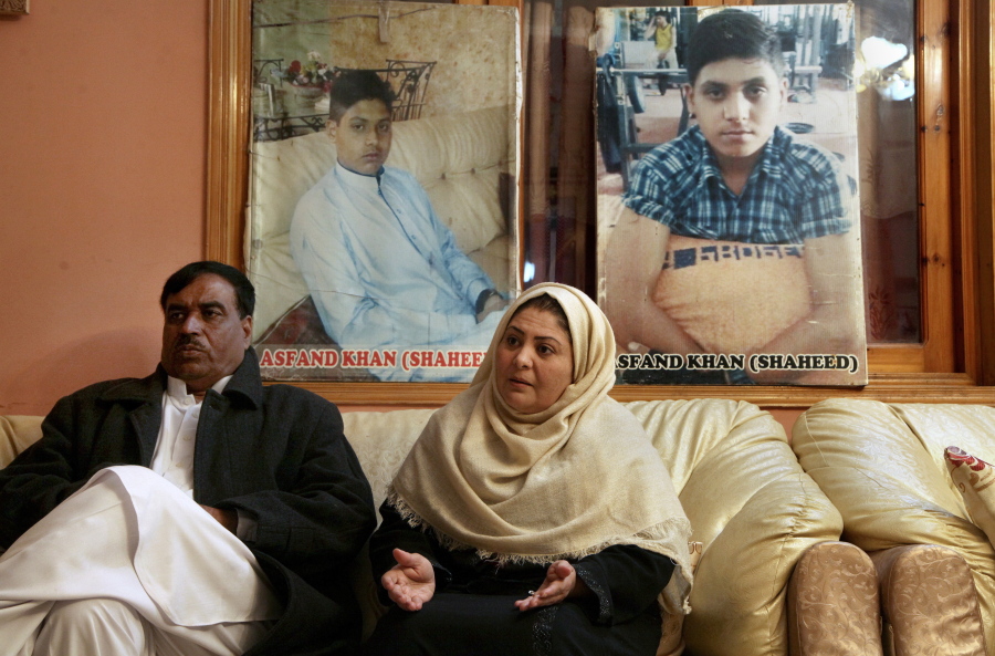 Pakistani mother Shahana with her husband Ajoon Khan sit next to photos of their son Asfand Khan, who was killed in a 2014 assault by Pakistani Taliban militants on an army public school, during an interview with The Associated Press, in Peshawar, Pakistan, Wednesday, Dec. 29, 2021. Each year on Jan. 17 Shahana bakes a cake and invites friends to her home to sing happy birthday, even light a candle but it's a birthday without the birthday boy, she says.