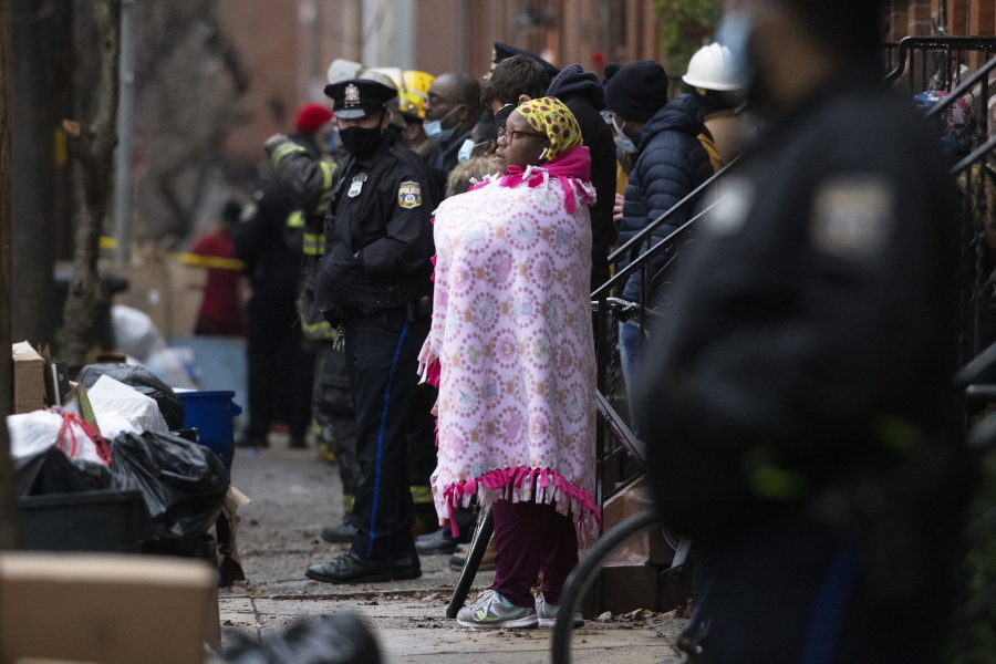 Bystanders watch as the Philadelphia fire department works at the scene of a deadly row house fire in Philadelphia on Wednesday, Jan. 5, 2022. Firefighters and police responded to the fatal fire at a three-story rowhouse in the city's Fairmount neighborhood around 6:40 a.m. and found flames coming from the second-floor windows, fire officials said. (Alejandro A.