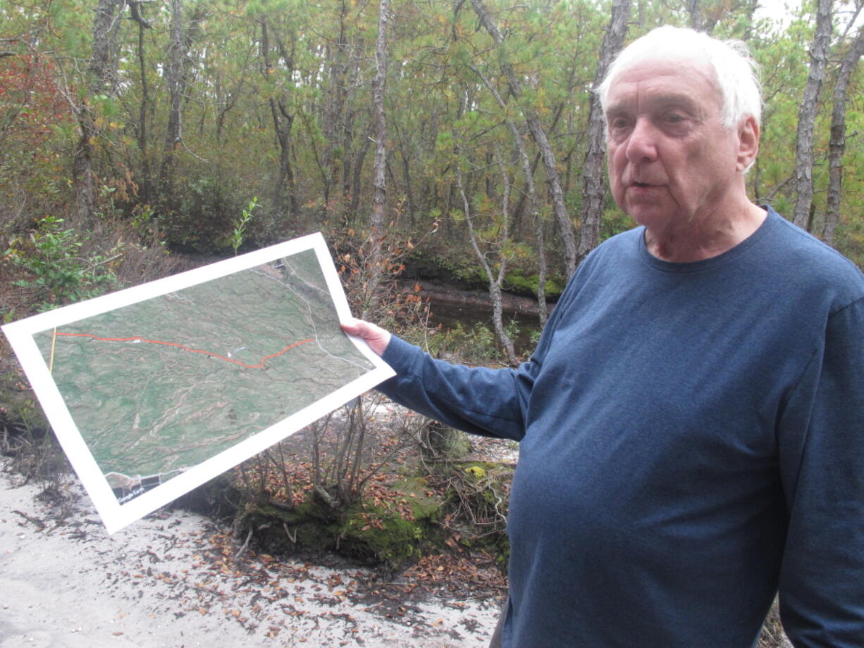 This Oct. 13, 2021, photo shows Albert Horner, a longtime nature photographer in New Jersey's Pinelands region, holding a map of areas that have sustained damage from illegal vehicle use in the woods in Shamong, N.J. Hikers and environmentalists who use New Jersey's Pinelands say the state is not doing enough to protect the fragile woodlands from damage from illegally used off-road vehicles.