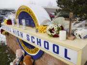 FILE - Memorial items are shown on the sign of Oxford High School in Oxford, Mich., Wednesday, Dec. 1, 2021. Officials planned to welcome students back to Oxford High School on Monday, Jan. 24, 2022, which is reopening for the first time since four students were killed and six students and a teacher were injured during a shooting at the school on Nov. 30, 2021. The students have been attending classes at other buildings since Jan. 10. A fellow student, Ethan Crumbley, 15, is charged with murder and other crimes. His parents also are facing charges.