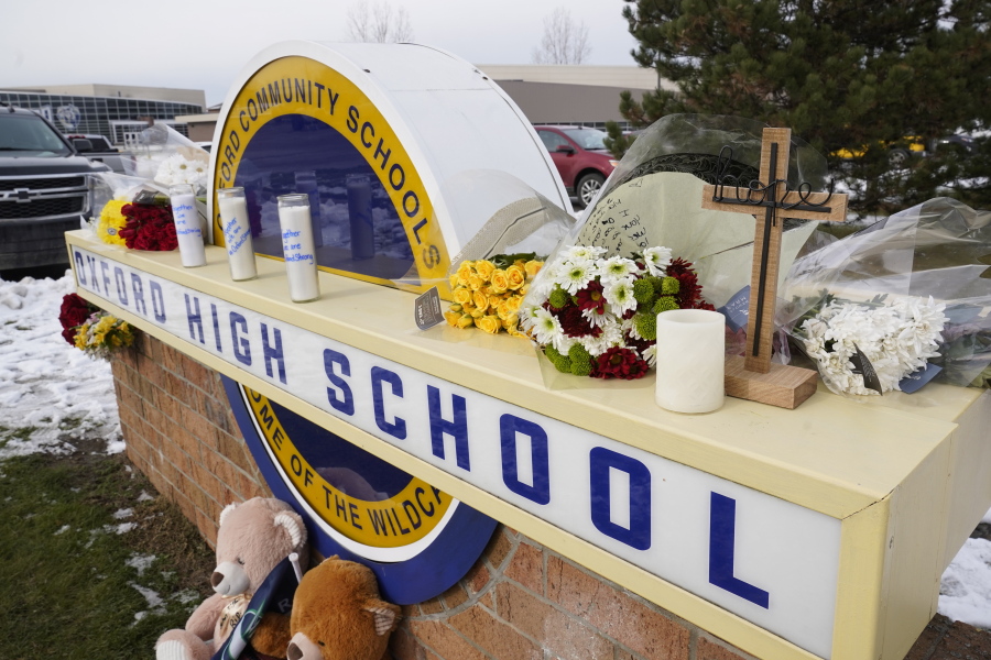 FILE - Memorial items are shown on the sign of Oxford High School in Oxford, Mich., Wednesday, Dec. 1, 2021. Officials planned to welcome students back to Oxford High School on Monday, Jan. 24, 2022, which is reopening for the first time since four students were killed and six students and a teacher were injured during a shooting at the school on Nov. 30, 2021. The students have been attending classes at other buildings since Jan. 10. A fellow student, Ethan Crumbley, 15, is charged with murder and other crimes. His parents also are facing charges.