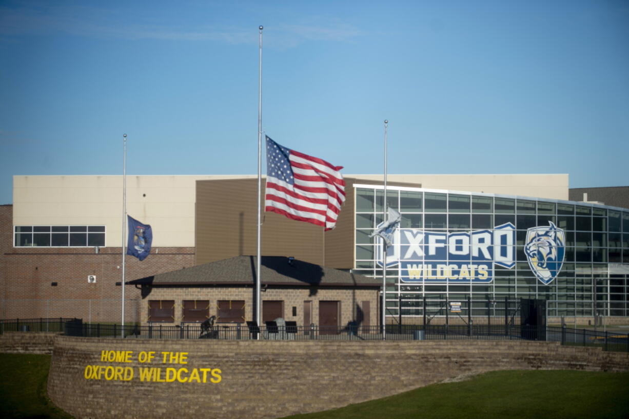 FILE - The American flag flies at half-staff on Thursday, Dec. 2, 2021, outside of Oxford High School in Oxford, Mich. Officials planned to welcome students back to Oxford High School on Monday, Jan. 24, 2022, which is reopening for the first time since four students were killed and six students and a teacher were injured during a shooting at the school on Nov. 30, 2021. The students have been attending classes at other buildings since Jan. 10. A fellow student, Ethan Crumbley, 15, is charged with murder and other crimes. His parents also are facing charges.