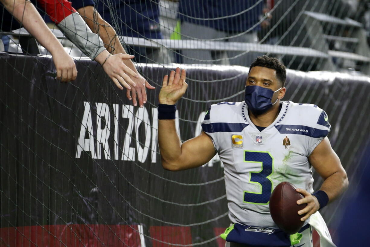 Seattle Seahawks quarterback Russell Wilson gets high-fives from fans after the Seahawks defeated the Arizona Cardinals after an NFL football game Sunday, Jan. 9, 2022, in Glendale, Ariz. The Seahawks won 38-30.