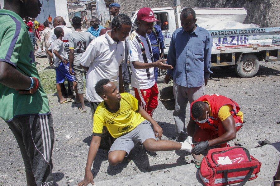 An injured man is treated by a medic at the scene of a blast in Mogadishu, Somalia Wednesday, Jan. 12, 2022. A large explosion was reported outside the international airport in Somalia's capital on Wednesday and an emergency responder said there were deaths and injuries.