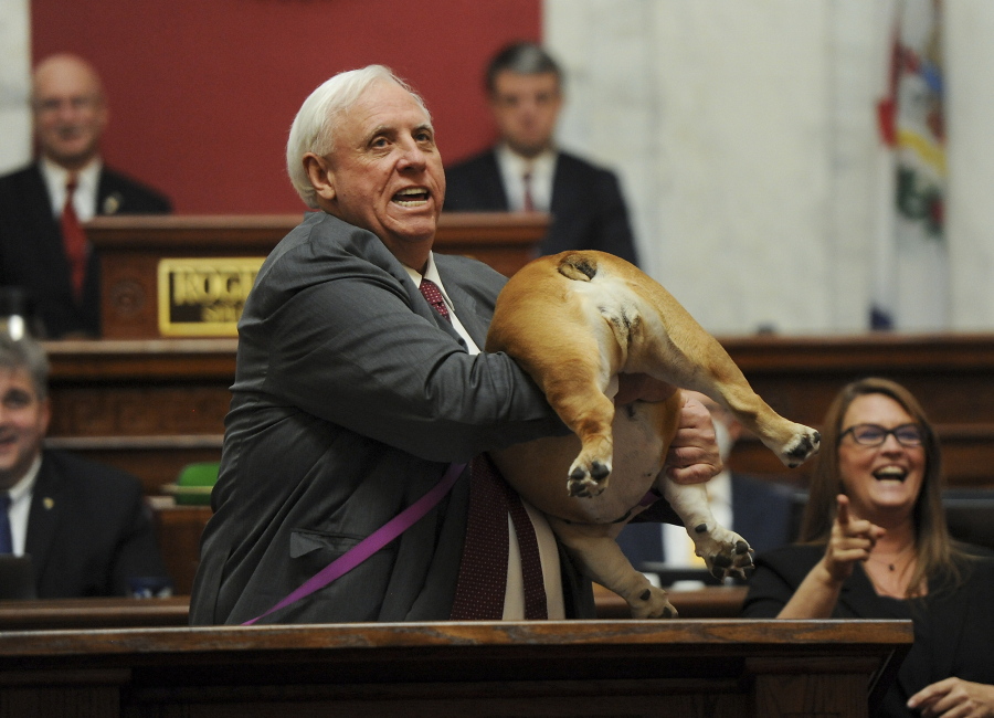 West Virginia Gov. Jim Justice holds up his dog Babydog's rear end as a message to people who've doubted the state as he comes to the end of his State of the State speech in the House chambers, Thursday, Jan. 27, 2022, in Charleston, W.Va.