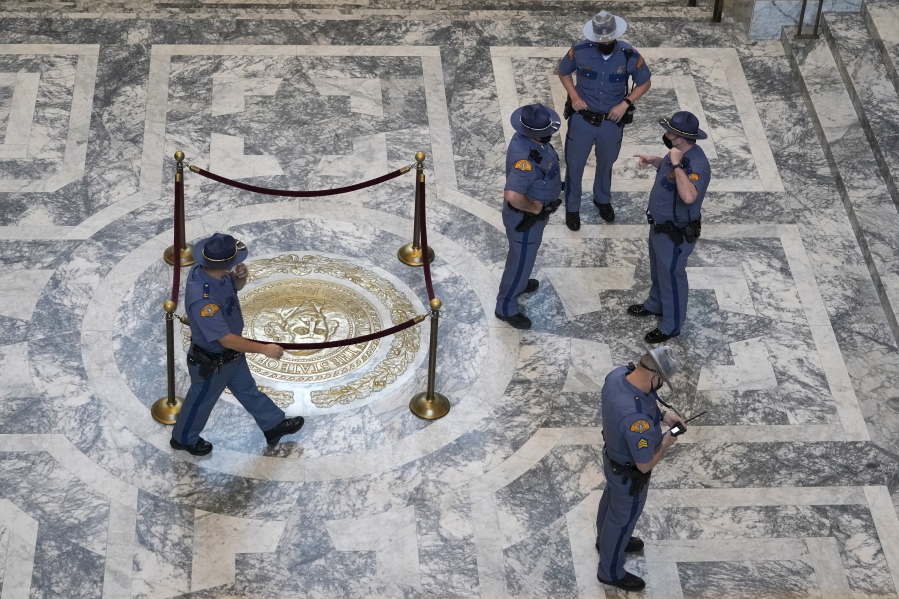 Washington State Patrol troopers stand near the state seal in the rotunda of the Legislative Building, Tuesday, Jan. 11, 2022, before Gov. Jay Inslee's scheduled State of the State address at the Capitol in Olympia, Wash. Due to cautions against COVID-19, Inslee will give the speech in the State Reception Room and it will be shown by streaming video to lawmakers meeting remotely. (AP Photo/Ted S.