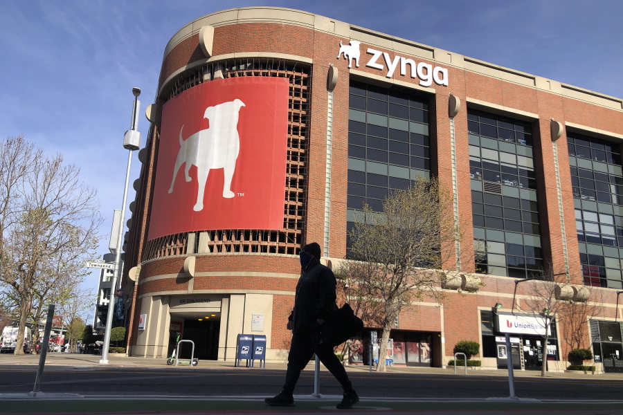 FILE - A pedestrian walks in front of a sign at Zynga in San Francisco, Tuesday, March 16, 2021. Take-Two Interactive, maker of Grand Theft Auto and Red Dead Redemption, is buying Zynga, maker of FarmVille and Words With Friends, in a cash-and-stock deal with an enterprise value of about $12.7 billion. Take-Two said Monday, Jan. 10, 2022, it anticipates $100 million in annual cost savings.