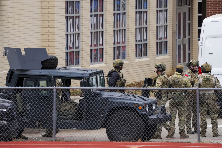 Law enforcement teams stage near Congregation Beth Israel while conducting SWAT operations in the 6100 block of Pleasant Run Road on Saturday, Jan. 15, 2022, in Colleyville, Texas. Authorities said a man took hostages Saturday during services at the Texas synagogue. (Smiley N.