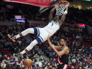 Minnesota Timberwolves forward Anthony Edwards (1) dunks over Portland Trail Blazers guard CJ McCollum during the second half of an NBA basketball game in Portland, Ore., Tuesday, Jan. 25, 2022.