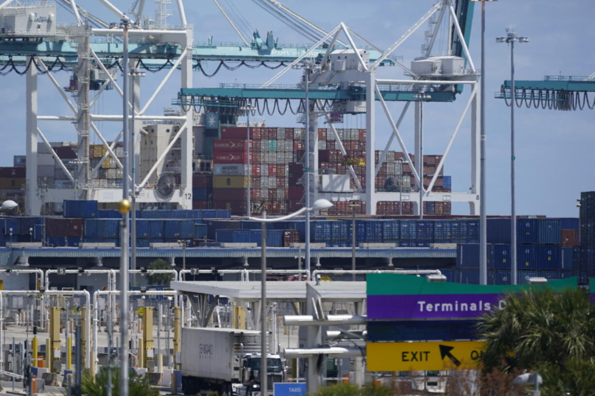 In this April 9, 2021 photo, cargo containers are shown stacked near cranes at PortMiami in Miami. The U.S. trade deficit narrowed to $67.1 billion in October, after hitting a record high the previous month, as a big rebound in exports helped to offset a much smaller rise in imports. The October deficit was 17.6% below the September record of $81.4 billion, the Commerce Department reported Tuesday, Dec. 7, 2021.