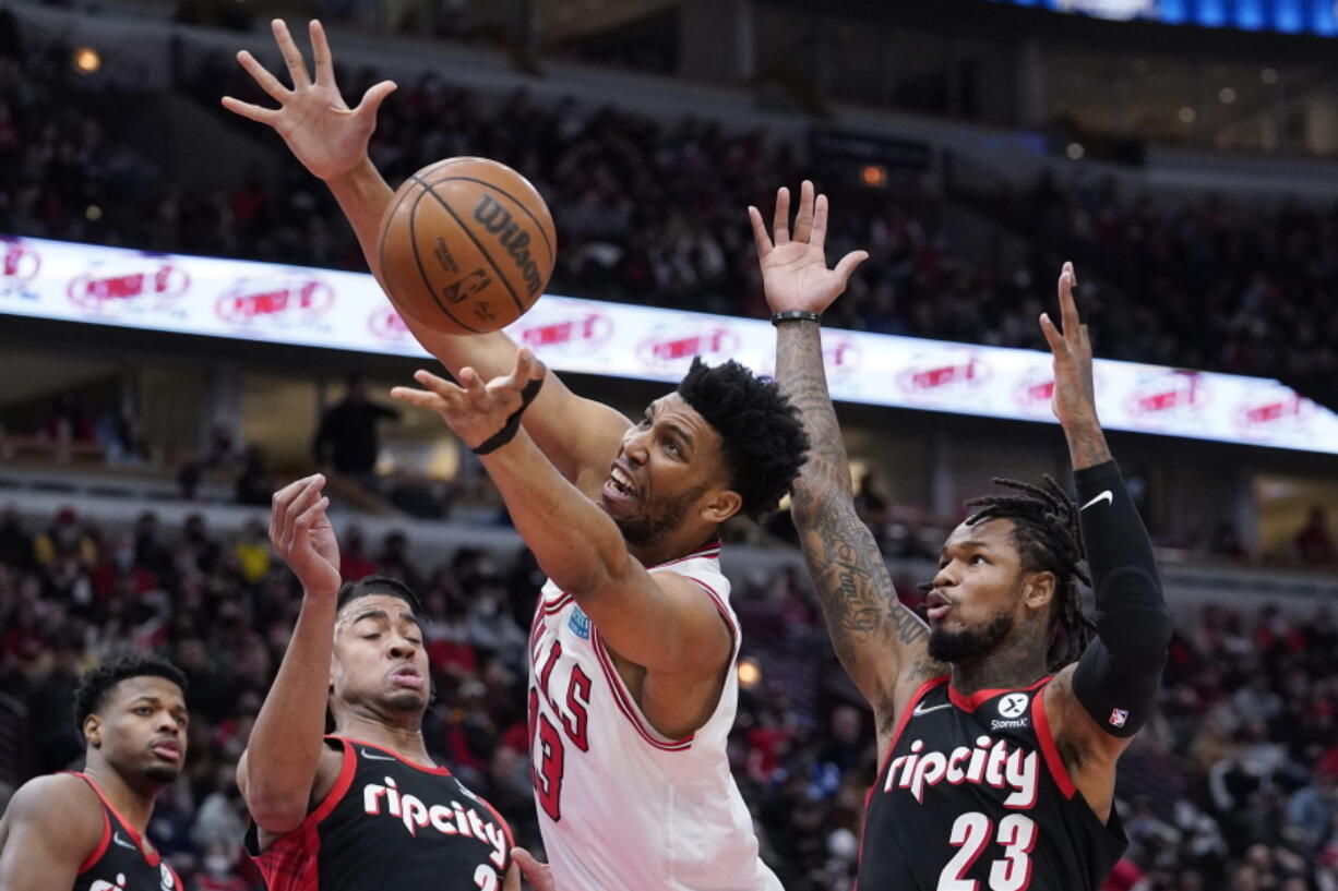Chicago Bulls center Tony Bradley, center, rebounds a ball against Portland Trail Blazers forward Trendon Watford, front left, and guard Ben McLemore (23) during the second half of an NBA basketball game in Chicago, Sunday, Jan. 30, 2022. (AP Photo/Nam Y.