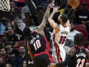 Miami Heat forward Caleb Martin (16) goes to the basket as Portland Trail Blazers guard Dennis Smith Jr. (10) defends during the first half of an NBA basketball game, Wednesday, Jan. 19, 2022, in Miami.