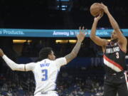 Portland Trail Blazers guard CJ McCollum, right, goes up for a three-point basket in front of Orlando Magic forward Chuma Okeke, left, during the first half of an NBA basketball game, Monday, Jan. 17, 2022, in Orlando, Fla. (AP Photo/Phelan M.