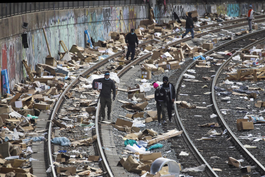 People rummage through stuff stolen from cargo containers littered on Union Pacific train tracks in the vicinity of Mission Boulevard on Saturday, Jan. 15, 2022, in Los Angeles.