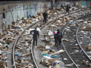 People rummage through stuff stolen from cargo containers littered on Union Pacific train tracks in the vicinity of Mission Boulevard on Saturday, Jan. 15, 2022, in Los Angeles.