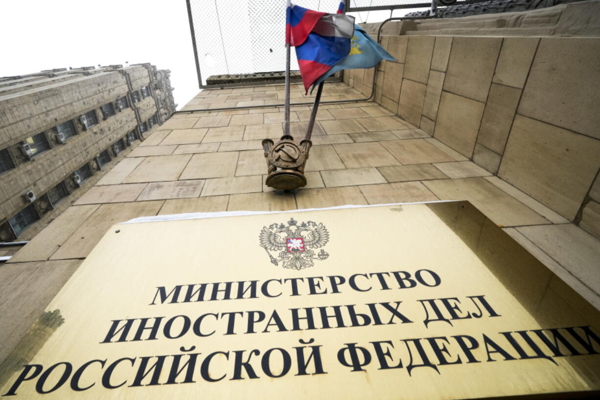 A Russian national flag flutters in the wind next to the sign of the Russian Foreign Ministry building in Moscow, Russia, Wednesday, Jan. 26, 2022. Russian Foreign Minister Sergey Lavrov said he and other top officials will advise President Vladimir Putin on the next steps after receiving written replies from the United States to the demands. Those answers are expected this week -- even though the U.S. and its allies have already made clear they will reject the top Russian demands.