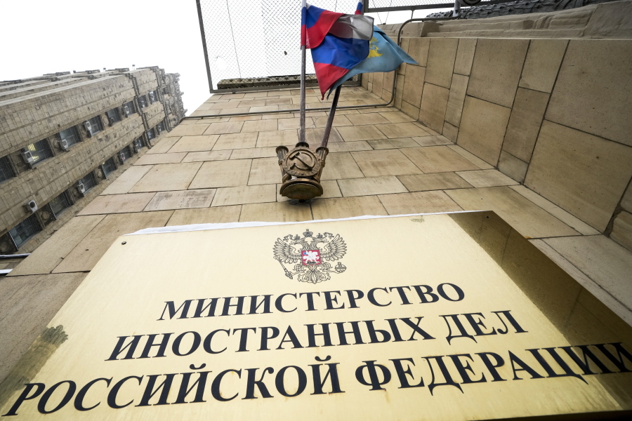 A Russian national flag flutters in the wind next to the sign of the Russian Foreign Ministry building in Moscow, Russia, Wednesday, Jan. 26, 2022. Russian Foreign Minister Sergey Lavrov said he and other top officials will advise President Vladimir Putin on the next steps after receiving written replies from the United States to the demands. Those answers are expected this week -- even though the U.S. and its allies have already made clear they will reject the top Russian demands.