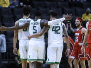 Oregon guard De'Vion Harmon (5) celebrates with Will Richardson (0) and Jacob Young (42) during the second half of the team's NCAA college basketball game against Utah in Eugene, Ore., Saturday, Jan. 1, 2022.