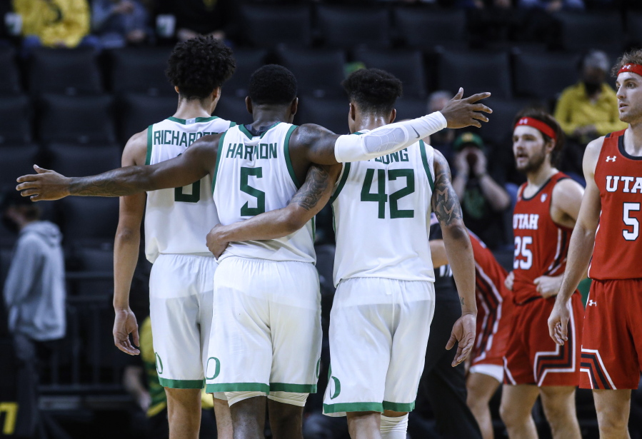 Oregon guard De'Vion Harmon (5) celebrates with Will Richardson (0) and Jacob Young (42) during the second half of the team's NCAA college basketball game against Utah in Eugene, Ore., Saturday, Jan. 1, 2022.