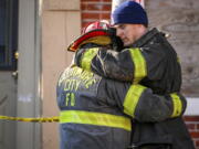 Baltimore City firefighters embrace at the scene of a vacant row house fire in Baltimore, Monday, Jan. 24, 2022.