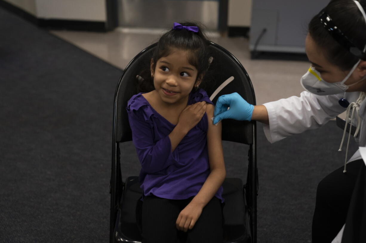 FILE - Elsa Estrada, 6, smiles at her mother as pharmacist Sylvia Uong applies an alcohol swab to her arm before administering the Pfizer COVID-19 vaccine at a pediatric vaccine clinic for children ages 5 to 11 set up at Willard Intermediate School in Santa Ana, Calif., Nov. 9, 2021. As of Tuesday, Jan. 11, 2022, just over 17% of children in the U.S. ages 5 to 11 were fully vaccinated, more than two months after shots for them became available. (AP Photo/Jae C.