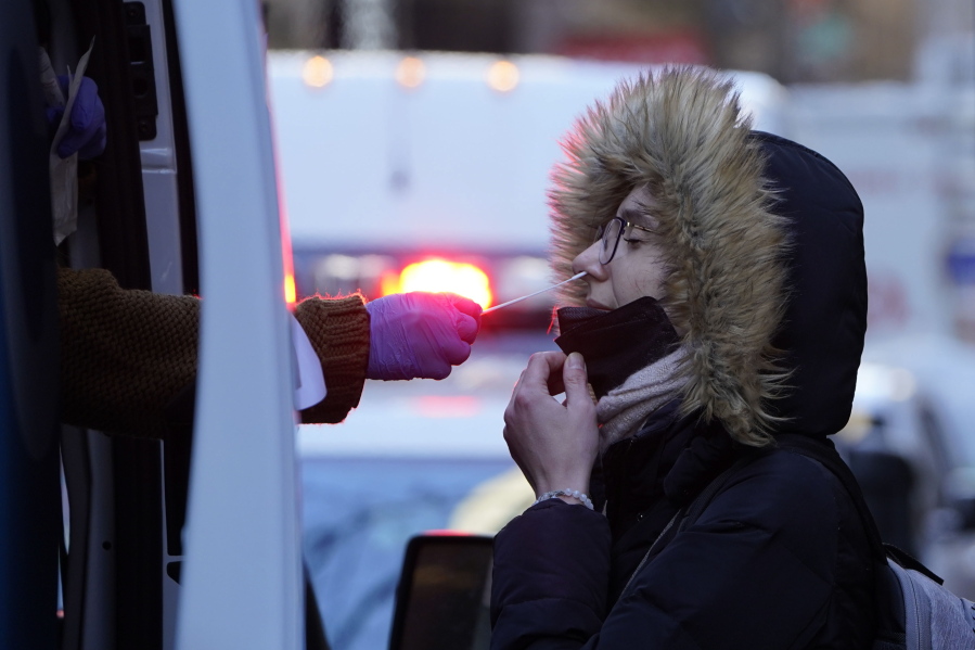 A woman wearing a winter coat gets tested for COVID-19 at a mobile testing site in New York, Jan. 11, 2022. Scientists are seeing signals that COVID-19?s alarming omicron wave may have peaked in Britain and is about to do the same in the U.S., at which point cases may start dropping off dramatically.