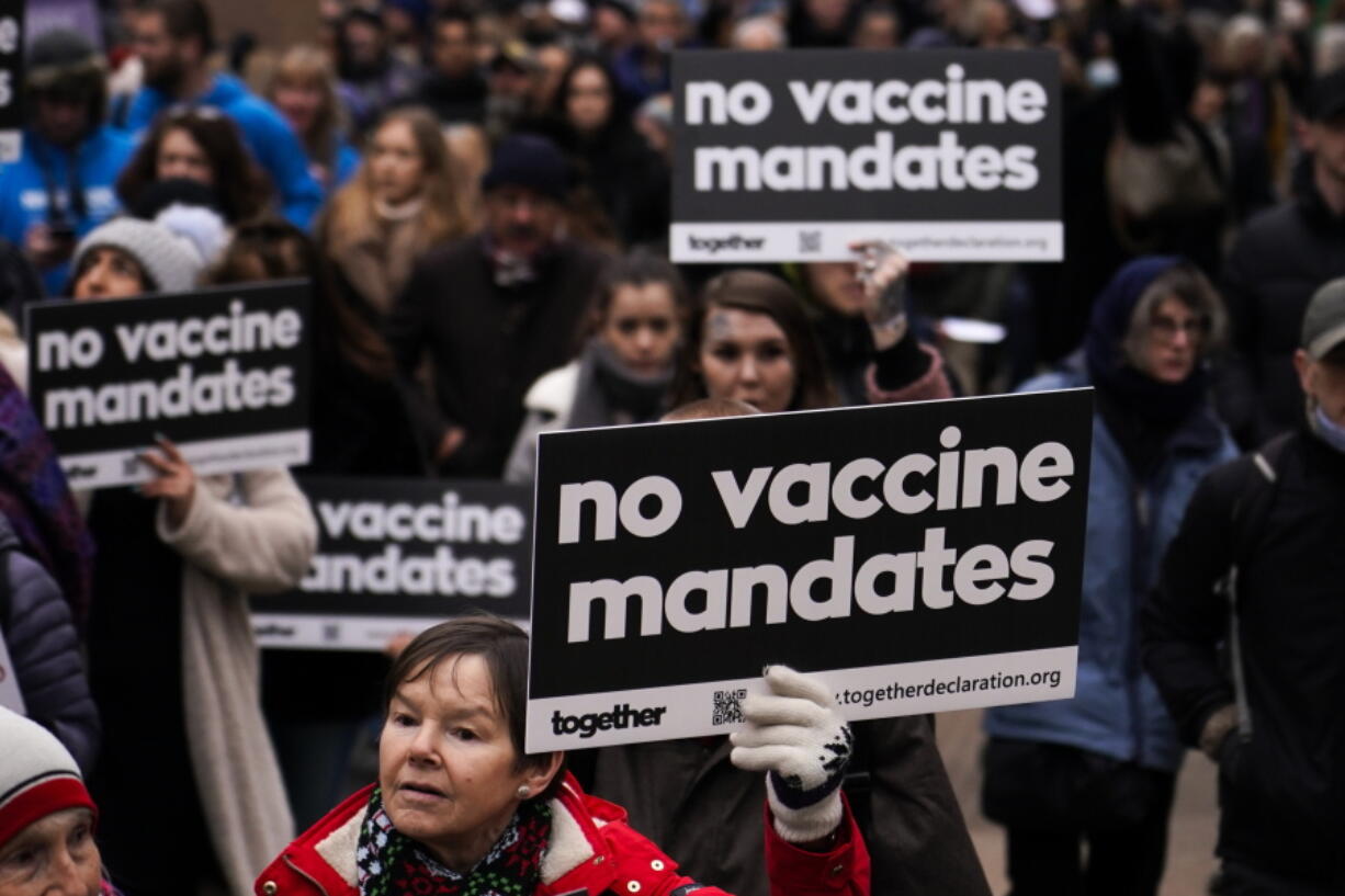 People hold placards as they attend a protest against vaccine passports Saturday in London.