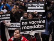 People hold placards as they attend a protest against vaccine passports Saturday in London.