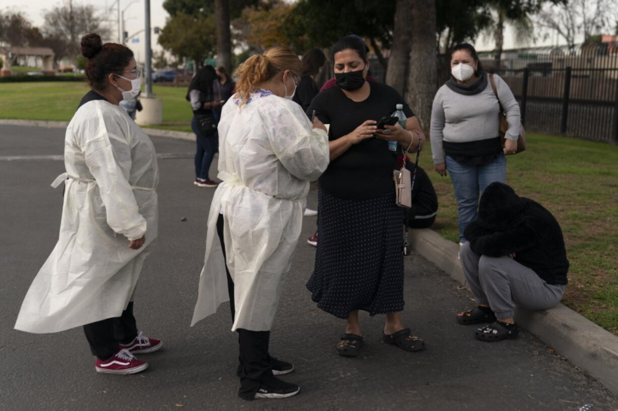 Two healthcare workers help residents check in at a mobile COVID-19 testing site in Paramount, Calif., Wednesday, Jan. 12, 2022. (AP Photo/Jae C.