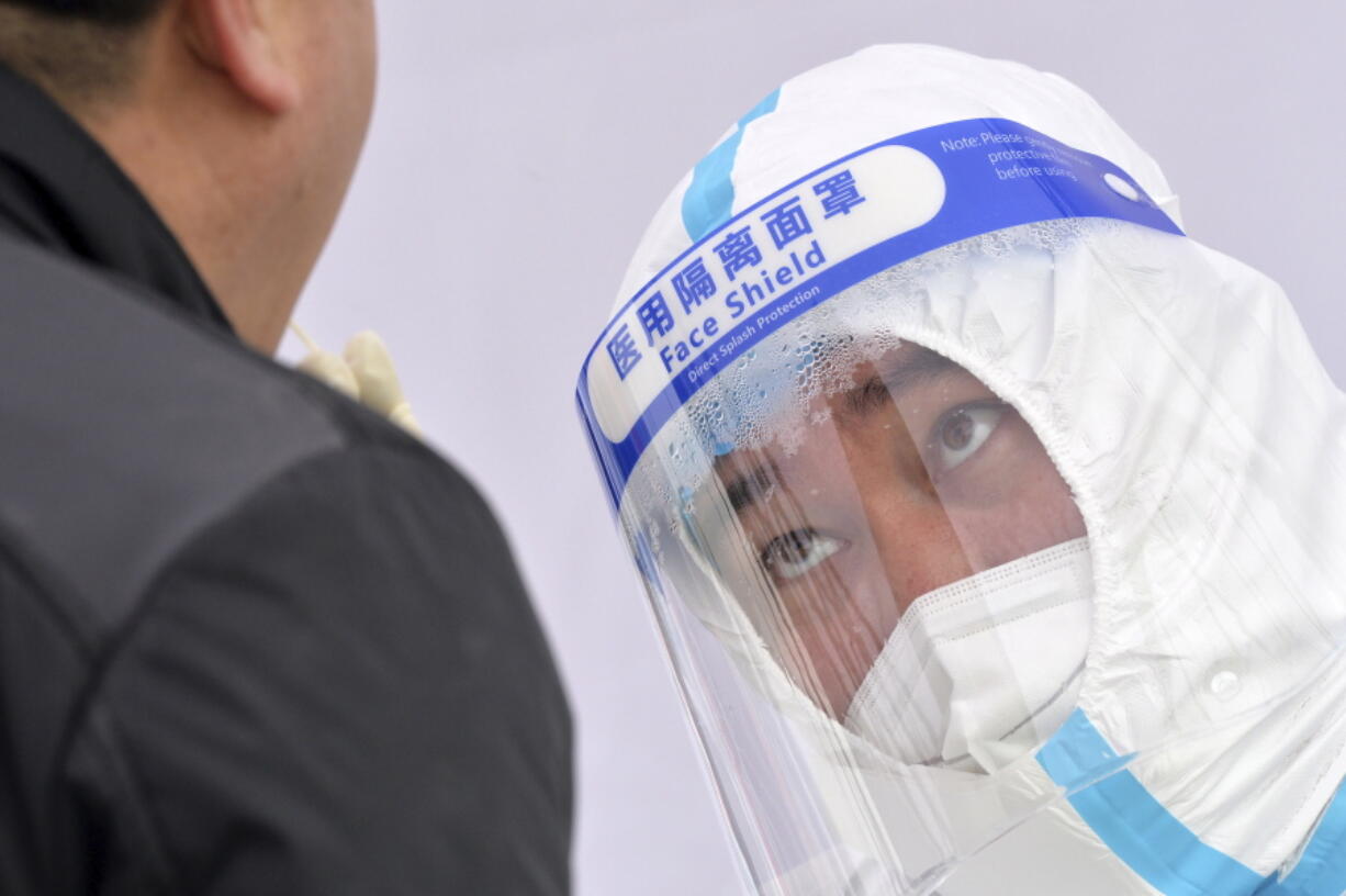 A medical worker's face shield fogs up as he takes sample from a resident during a second round of COVID-19 testing in northern China's Tianjin Municipality on Wednesday, Jan. 12, 2022. The northern Chinese city of Tianjin ordered a second round of COVID-19 testing on all 14 million residents Wednesday following the discovery of 97 cases of the omicron variant during initial screenings that began Sunday.