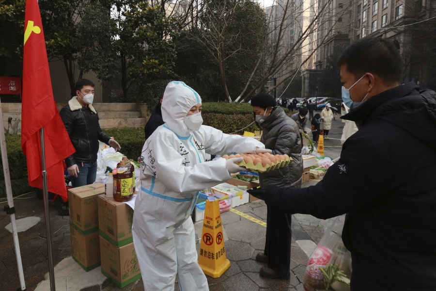 A community volunteer hands over eggs to a buyer at a temporary food store to provide supplies to residents outside a residential block in Xi'an city in northwest China's Shaanxi province Monday, Jan. 03, 2022. Authorities in the northern Chinese city of Xi'an say they can provide food, health care and other necessities for the roughly 13 million under an almost two-week old lockdown. But some residents describe difficulties obtaining supplies and frustration and the economic impact on the city that is home to the famed Terracotta warriors, along with major industries.
