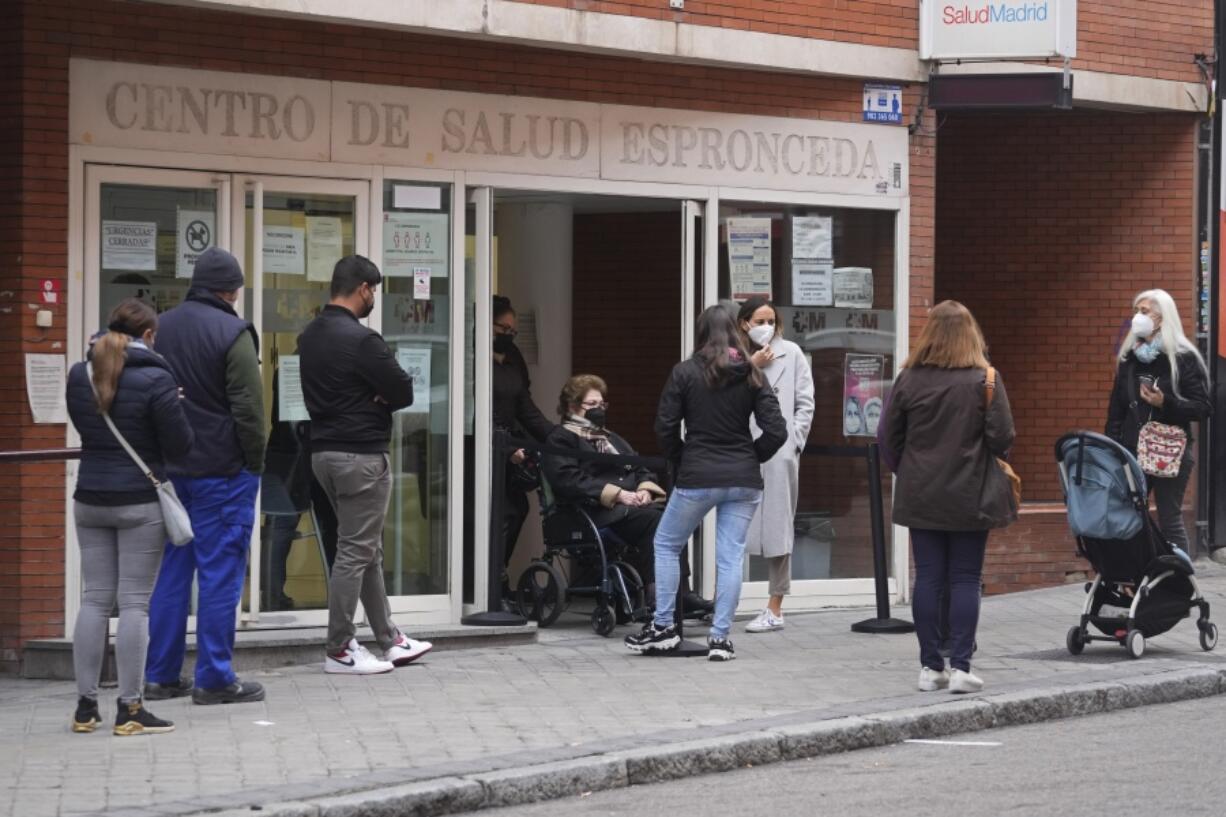 People queue outside a local health center in Madrid, Spain, Tuesday, Jan. 4, 2022. An unprecedented number of coronavirus infections is once again exposing the underfunding and shortcomings of public health care systems, even in developed parts of Europe. Spain is especially feeling the crunch.