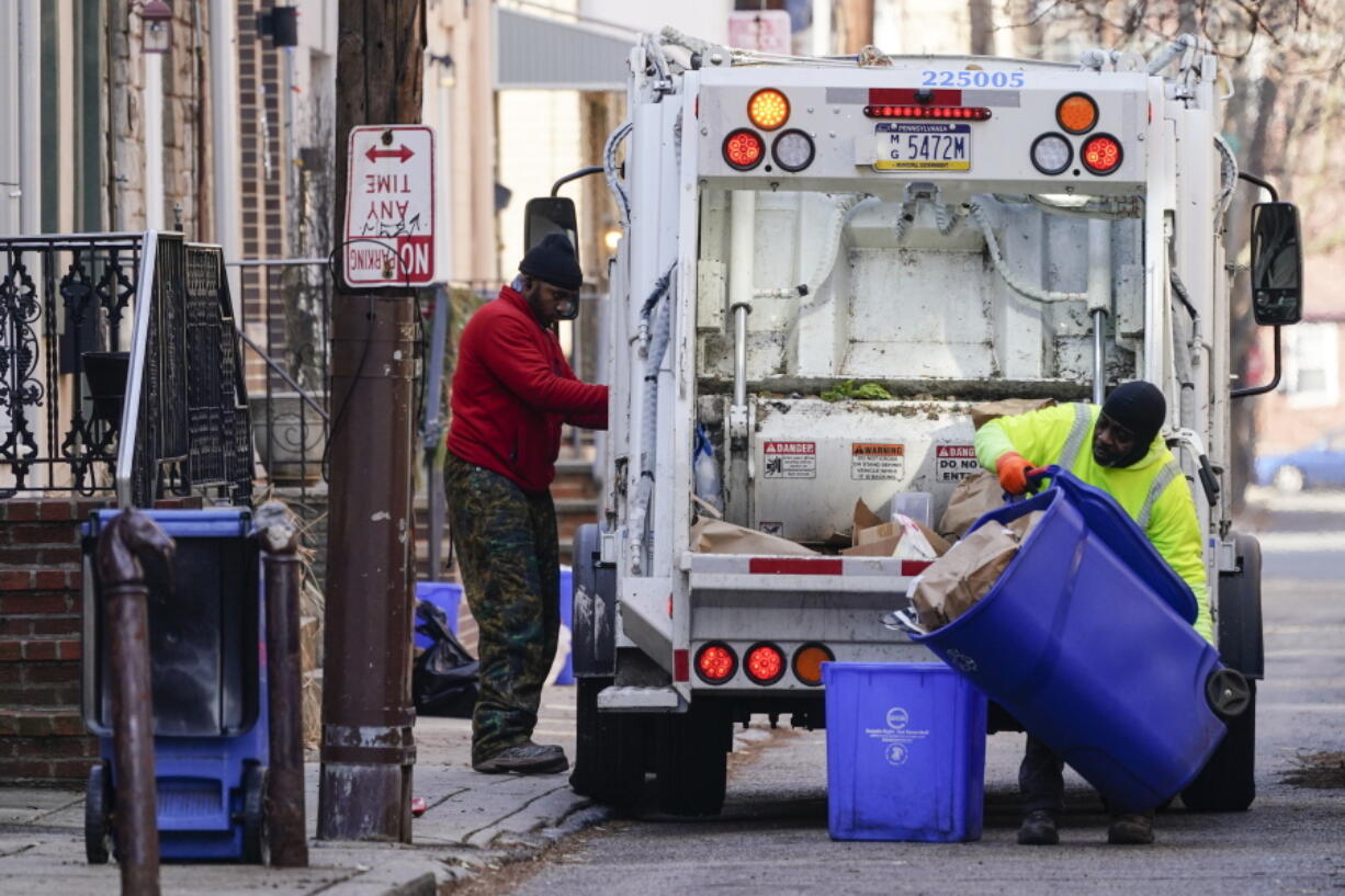 Municipal sanitation workers collect trash in Philadelphia, Thursday, Jan. 13, 2022. The omicron variant is sickening so many sanitation workers around the U.S. that waste collection in Philadelphia and other cities has been delayed or suspended.