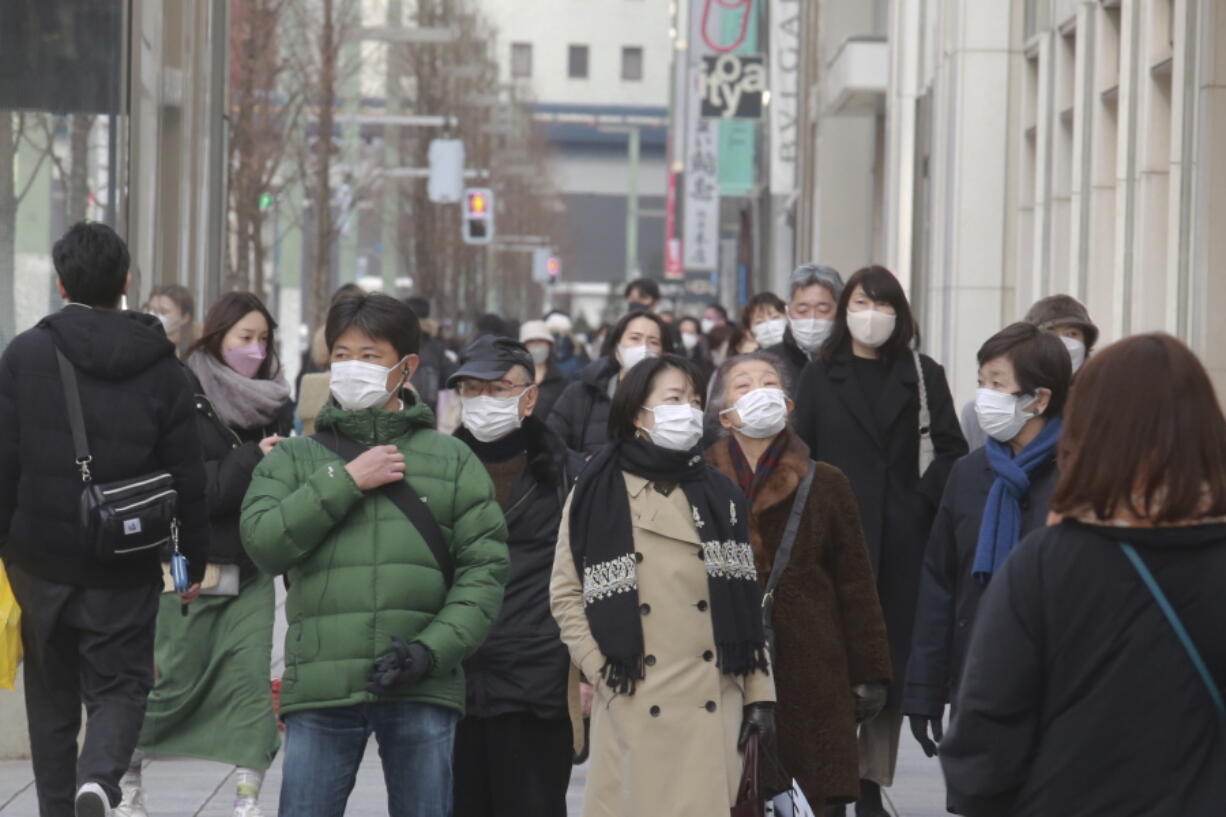 People wearing face masks to protect against the coronavirus walk on a street Wednesday, Jan. 26, 2022.