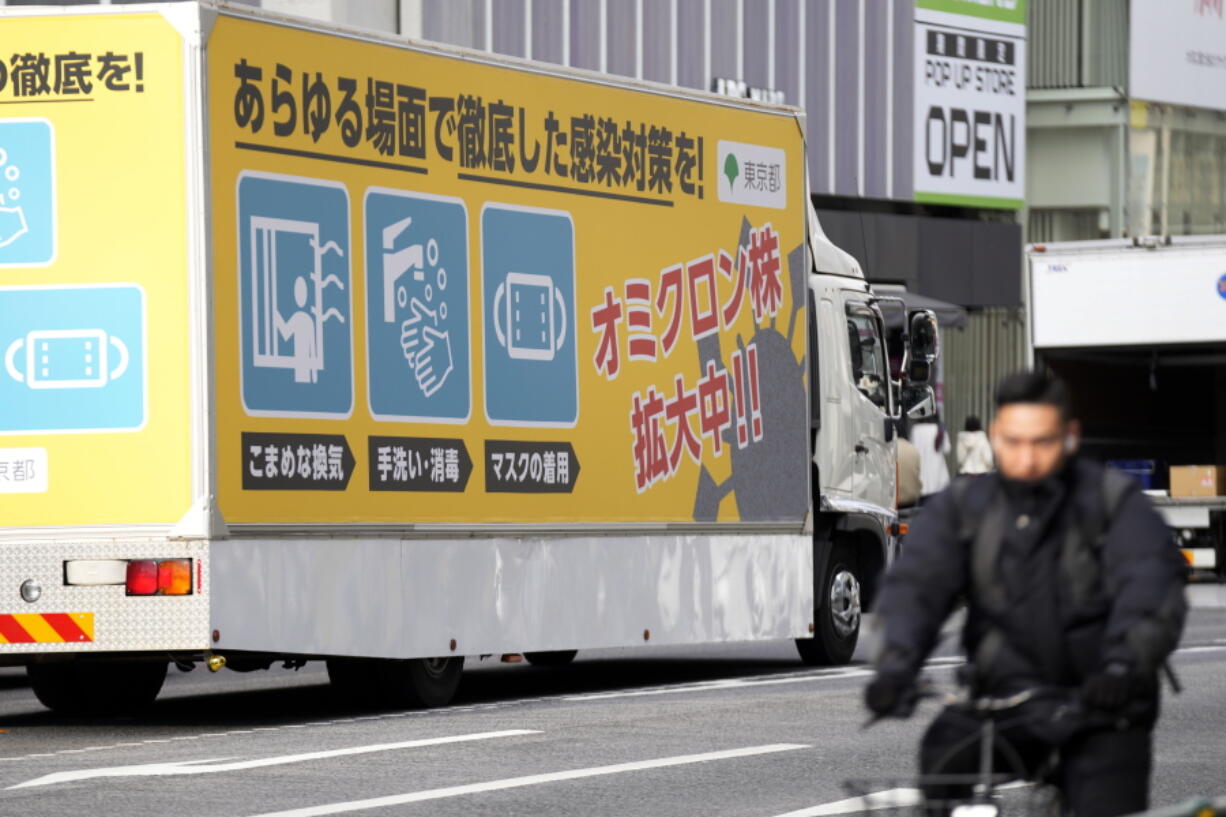 A truck with a public awareness notice on the omicron coronavirus variant moves though a busy shopping street Friday, Jan. 28, 2022, in Tokyo.