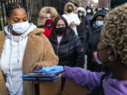 FILE - People line up and receive test kits to detect COVID-19 as they are distributed in New York on Dec. 23, 2021. The COVID-19 surge caused by the omicron variant means once-reliable indicators of the pandemic's progress are much less so, complicating how the media is able to tell the story.